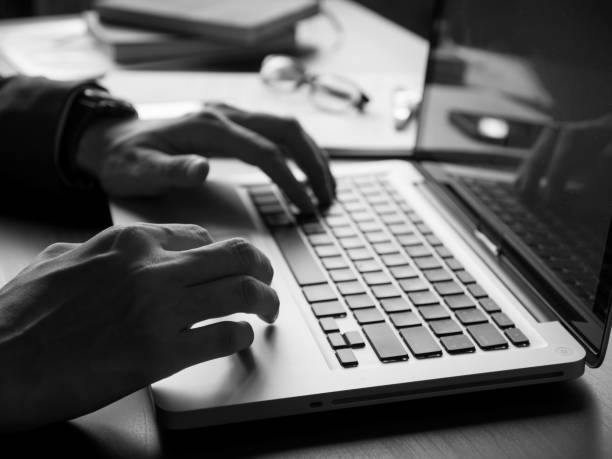 Close up of businessman using laptop on the office desk. Black and White tone